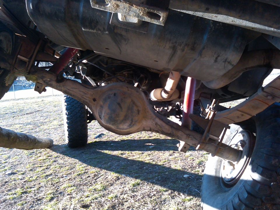 1988 Ford Bronco rear axle, leaf springs, and fuel tank. Off-road tires visible