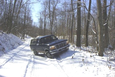 1995 Ford Bronco - A 1995 Ford Bronco navigates a snowy path in a wooded area.