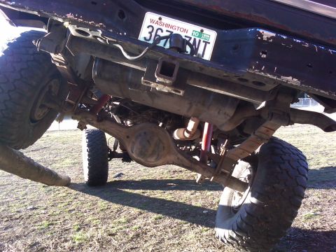 1988 Ford Bronco - The underside of a vehicle shows its rear axle, leaf springs, and exhaust system.