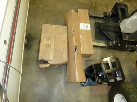 1992 Ford Mustang - Cardboard boxes and black metal vehicle parts are laid out on a concrete floor, suggesting an automotive repair or parts storage area.