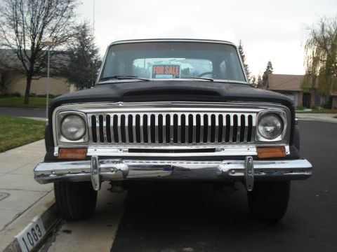 1977 Jeep Cherokee - Front view of a 1977 Jeep Cherokee, identifiable by its grille, with a 'For Sale' sign in the window.
