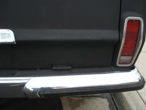 1977 Jeep Cherokee - Rear view of a black 1977 Jeep Cherokee showing its tailgate, chrome bumper, and taillight.