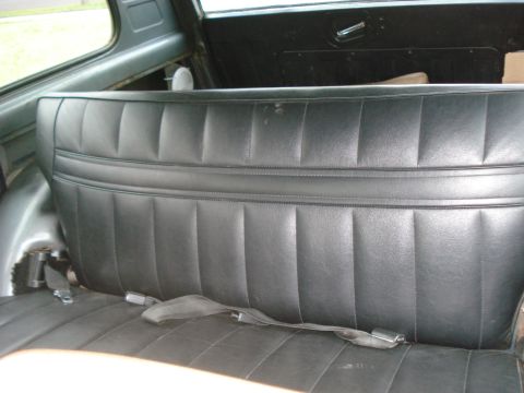 1977 Jeep Cherokee - The interior of a vehicle shows a black vinyl rear seat with seatbelts.