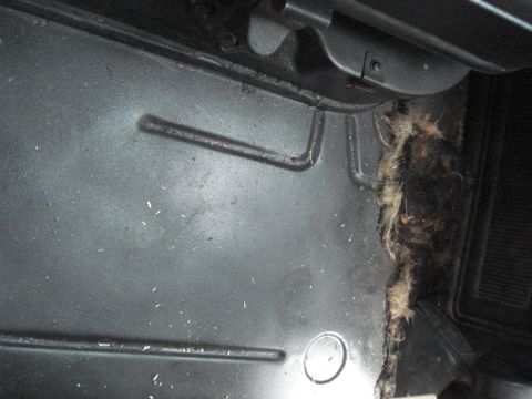 1977 Jeep Cherokee - The interior floor of a vehicle shows some wear and tear, with visible insulation and debris on the right side.