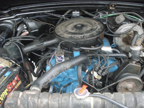 1977 Jeep Cherokee - Close-up view of an engine bay, showing the engine block, air cleaner, and battery with visible text.
