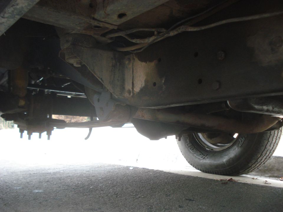 Underside view of vehicle frame and suspension, showing leaf springs and tire