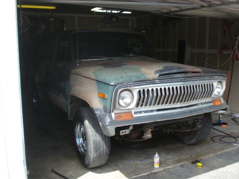1977 Jeep Cherokee - A camouflage-painted Jeep Wagoneer sits in a garage, appearing to be undergoing some work.