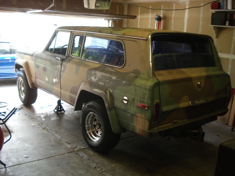 1977 Jeep Cherokee in camouflage paint, rear 3/4 view, in garage
