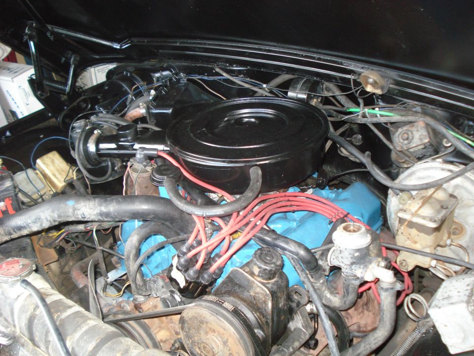 Engine bay with V8 engine, air cleaner, spark plug wires, and power steering pump visible