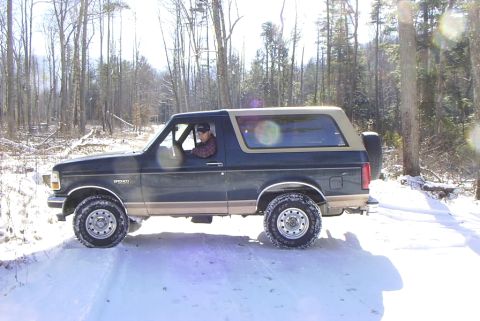 1995 Ford Bronco - A 1995 Ford Bronco navigates a snow-covered road through a wooded area.