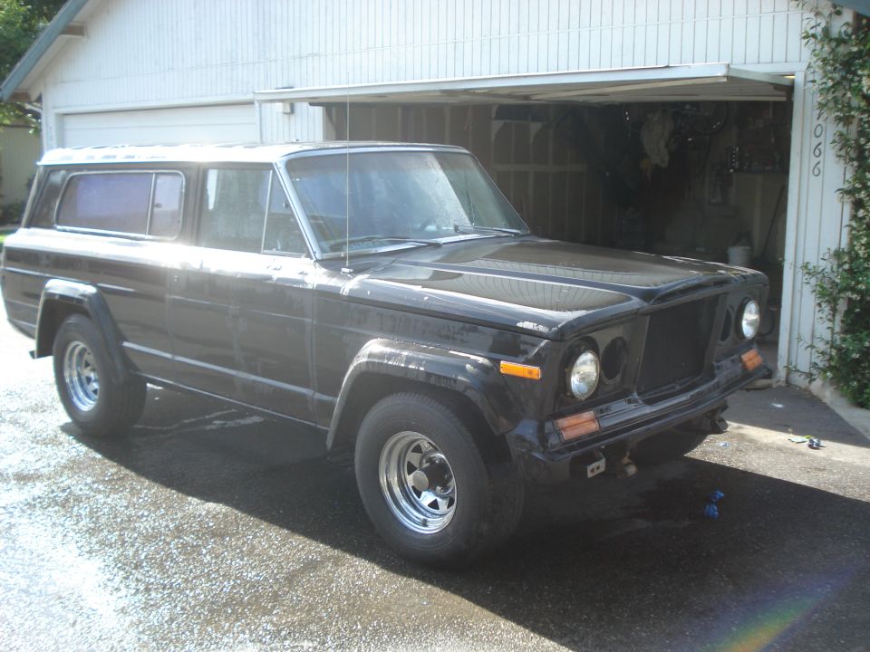 Black Jeep Wagoneer parked in front of a garage