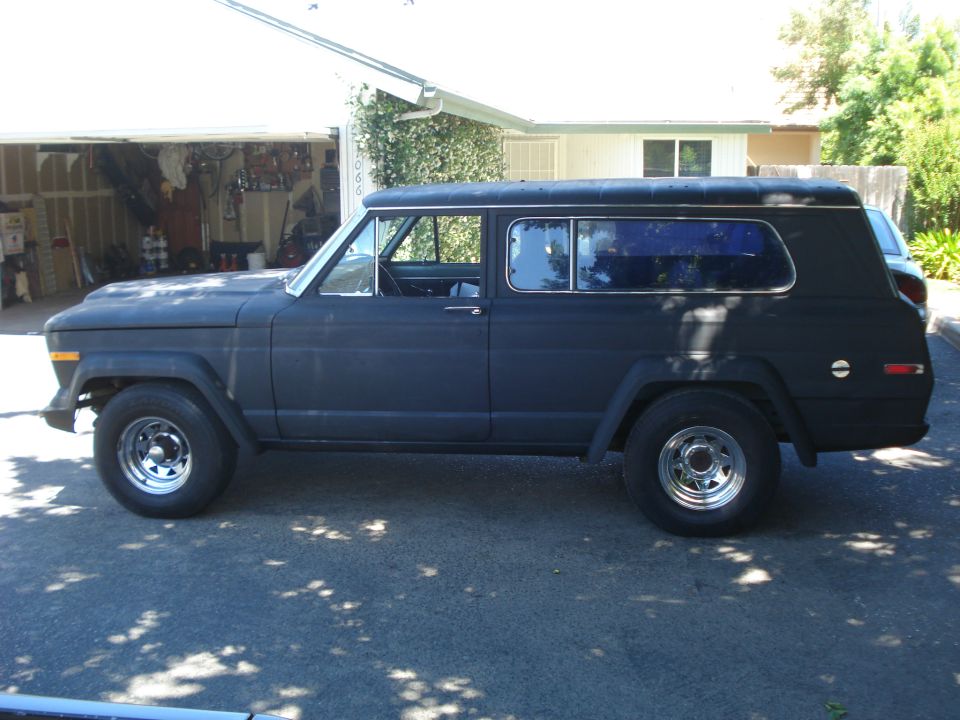 Black Jeep Wagoneer from the side, matte finish, chrome wheels, parked in driveway