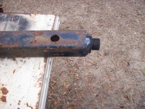 1982 Ford F-100 - Rusty metal part with a hole and threaded end resting on a surface.