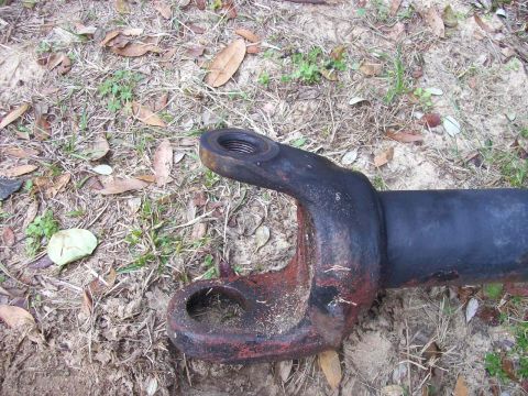 1982 Ford F-100 - A close-up view of a rusty driveshaft component lying on the ground.