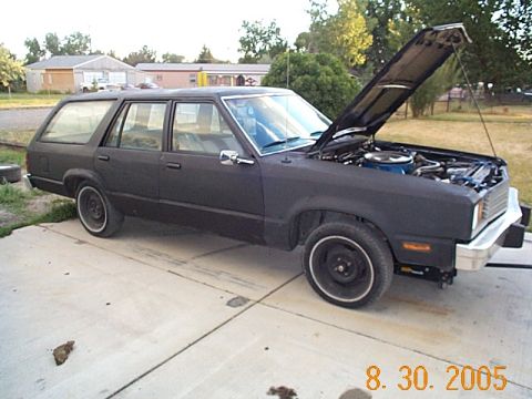 1982 Mercury Zephyr - A black station wagon sits in a driveway with its hood up, revealing the engine compartment.