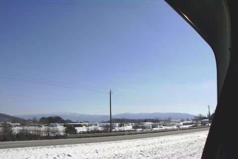 1995 Ford Bronco - A winter scene unfolds with snow-covered ground and a clear sky, offering a glimpse of distant structures and mountains.