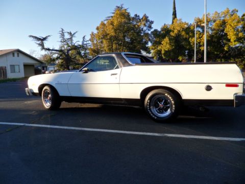 1973 Ford Ranchero - A white 1973 Ford Ranchero with a black vinyl top is parked on asphalt under a clear sky.