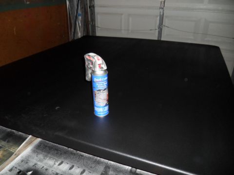 1973 Ford Ranchero - A can of truck bed coating rests on a freshly painted black surface, likely a vehicle part.