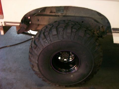 1989 Ford Bronco - Close-up of a vehicle's rear wheel well and tire, with visible rust on the frame.