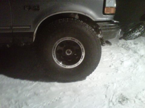 1994 Ford F-150 - The front wheel and fender of a gray 1994 Ford F-150 are visible in the snow.
