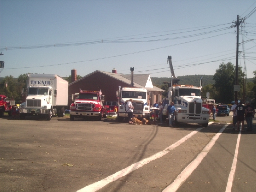 Several trucks parked in a lot with people around them