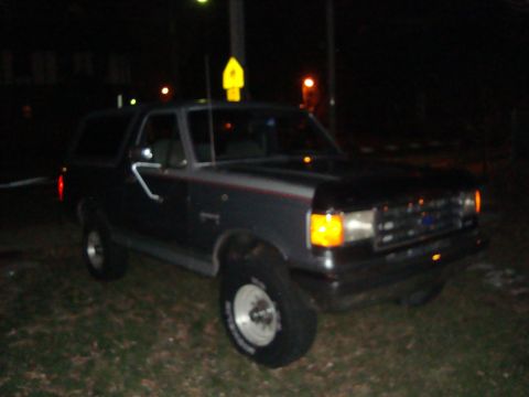 1991 Ford Bronco - A 1991 Ford Bronco is parked outside at night, illuminated by streetlights and its own headlights.