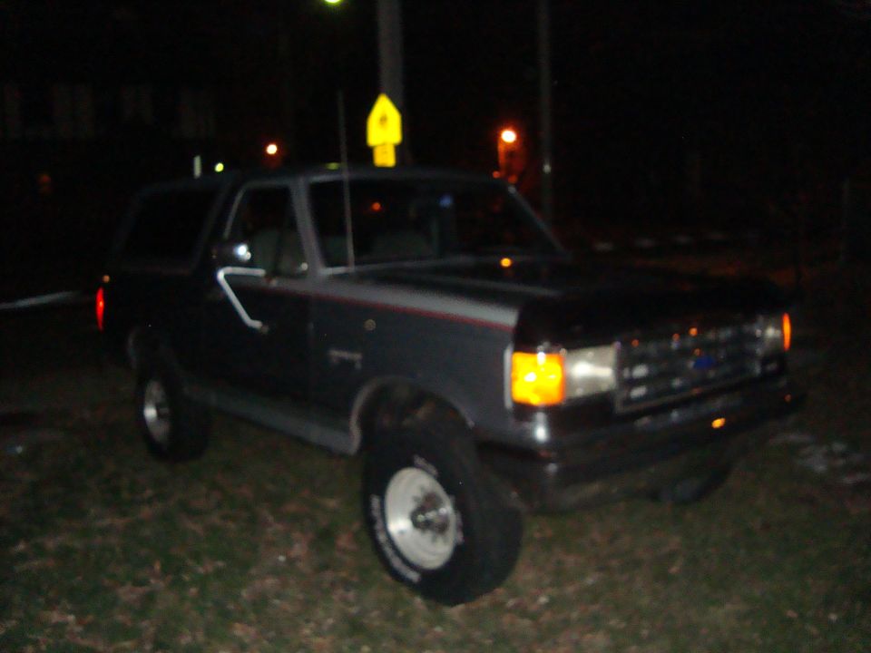Dark colored Ford Bronco parked at night. It's a 1991 model