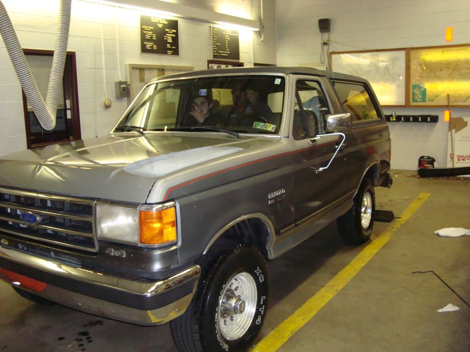 Gray two-tone Ford Bronco 4x4 parked inside a garage bay, front three-quarter view