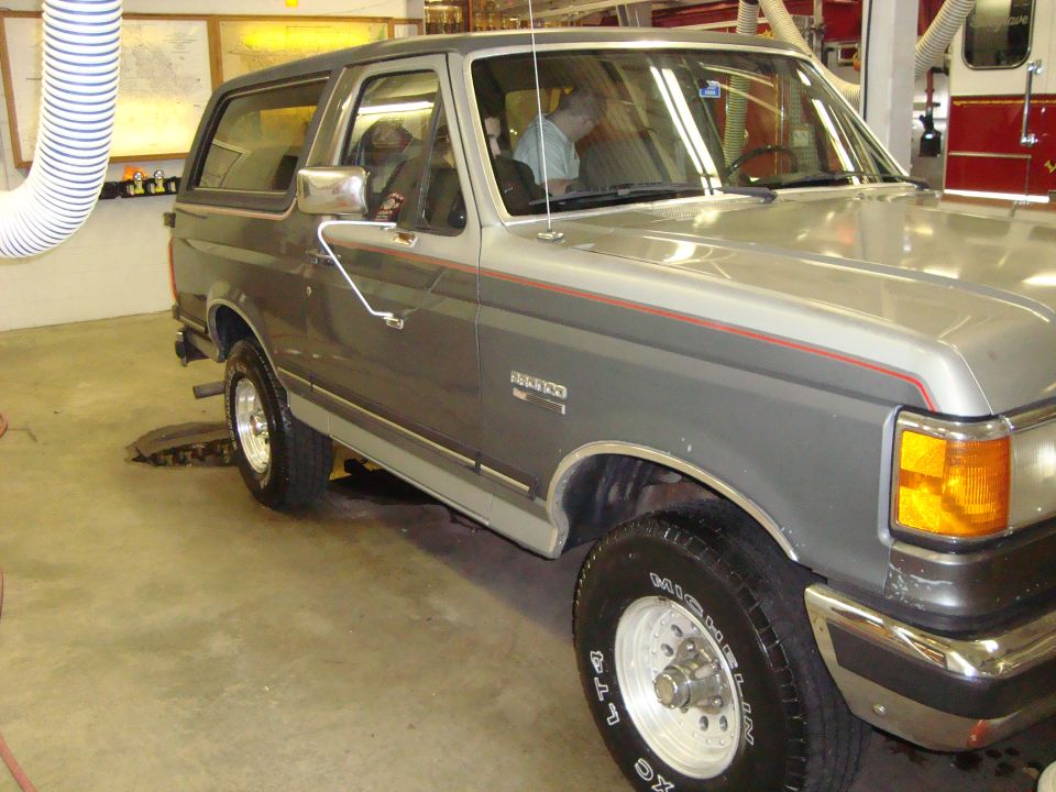 Gray and silver two-tone Ford Bronco with red pinstripes, seen from the front three-quarter angle