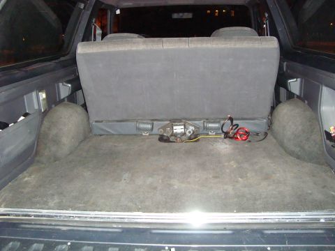 1991 Ford Bronco - The rear cargo space of an SUV is shown, a folded seat and exposed wiring for a trailer hitch connection.