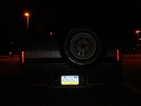 1991 Ford Bronco - Rear view of a 1991 Ford Bronco at night, showing the spare tire and Pennsylvania license plate.