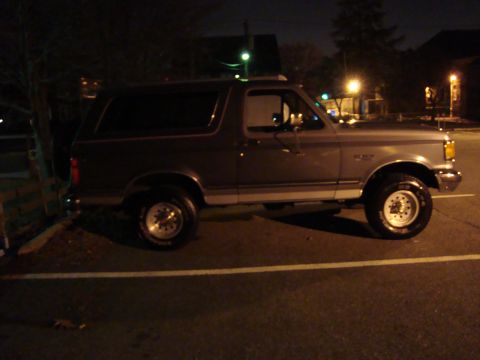 1991 Ford Bronco - A Ford Bronco is parked in a lot at night, illuminated by streetlights.