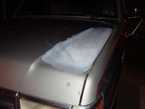 1991 Ford Bronco - The hood of a silver Ford Bronco shows significant damage to its clear coat, with a white cloth placed over the affected area.