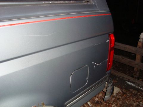 1991 Ford Bronco - Rear view of a gray SUV showing damage to the quarter panel and red pinstriping.