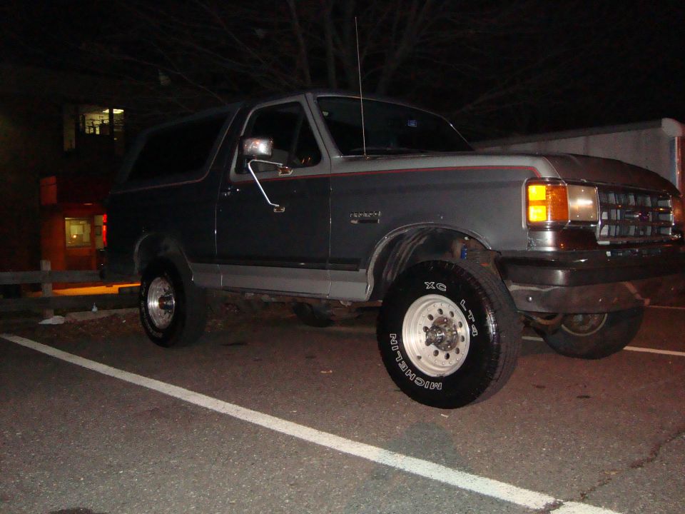 Gray Ford Bronco parked at night. Has red and gray trim on the side