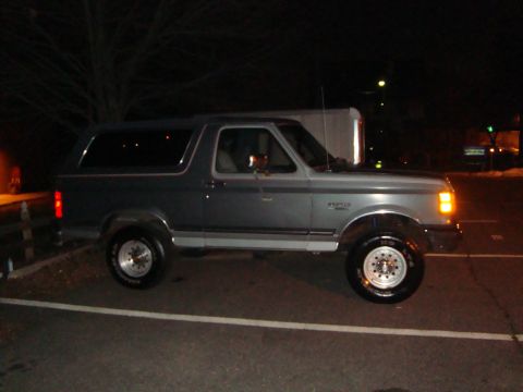 1991 Ford Bronco - A gray Ford Bronco is parked outdoors at night, showing its side profile.
