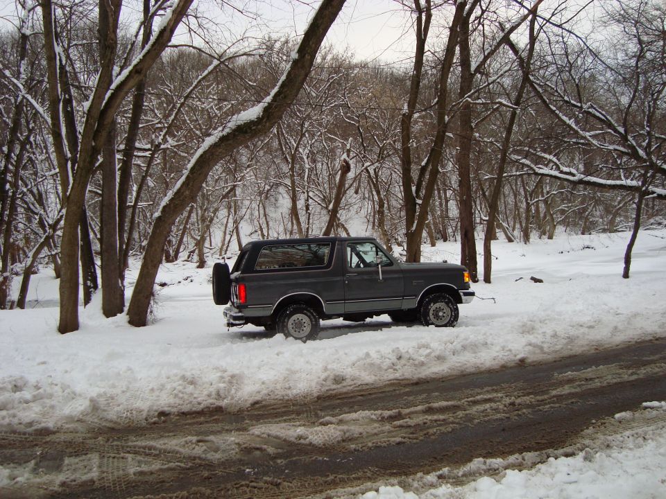 1991 Ford Bronco parked on a snowy road with trees in the background