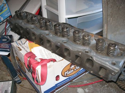 1981 Ford Bronco - A gray engine cylinder head with visible valve springs rests on a box.