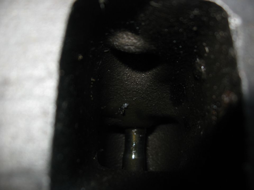 Black engine part with a metal pin protruding from a dark recess