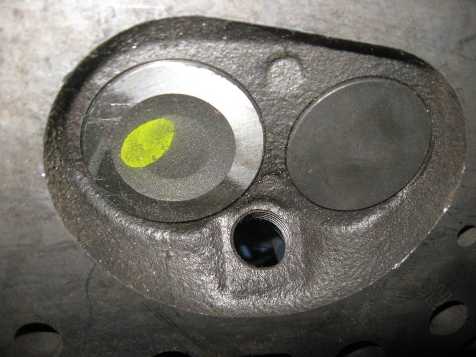 Engine cylinder head with two valve openings and a yellow mark on one valve seat