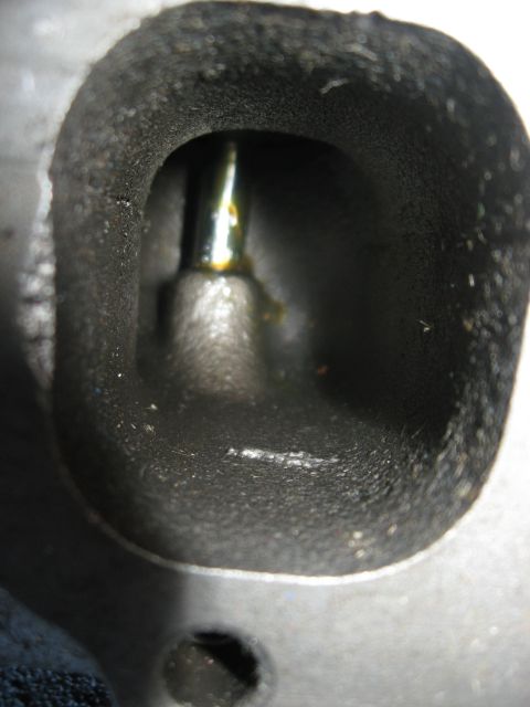1981 Ford Bronco - Macro looking straight into a cylinder head's rectangular intake port, showing the as-cast rough runner walls and the valve stem and guide…