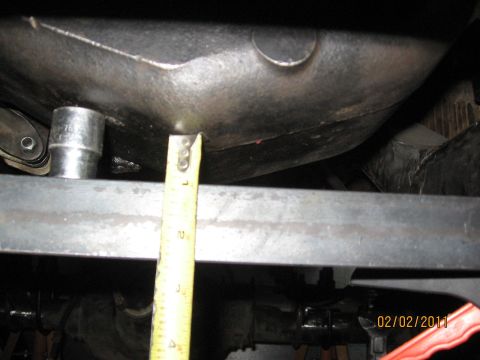 1961 International Scout 800 - A tape measure is used to gauge a component of a vehicle's undercarriage, with a socket wrench visible.