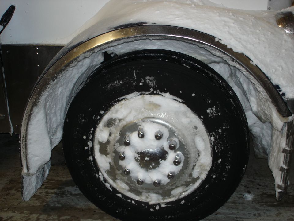 Close-up of a snow-covered wheel and fender of a large vehicle