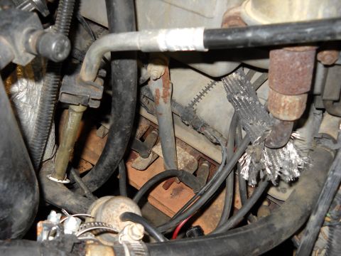 1993 Ford C-150 (Centurion Conversions) - Close-up view of engine components, including an exhaust pipe and frayed wiring harness.