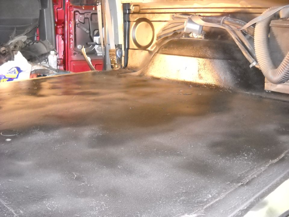 Red interior cargo area with black spray-on bed liner and visible hoses