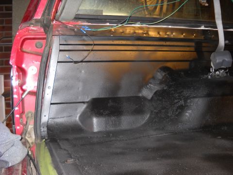 1993 Ford C-150 (Centurion Conversions) - The interior of a red truck bed shows a black spray-on liner and some exposed wiring near the rear window.