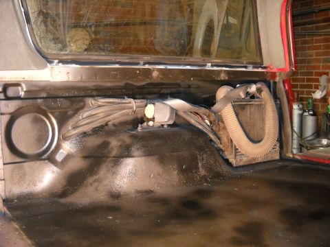 1993 Ford C-150 (Centurion Conversions) - The rear interior of a vehicle shows exposed wiring, a large flexible hose, and a box unit, possibly for climate control.