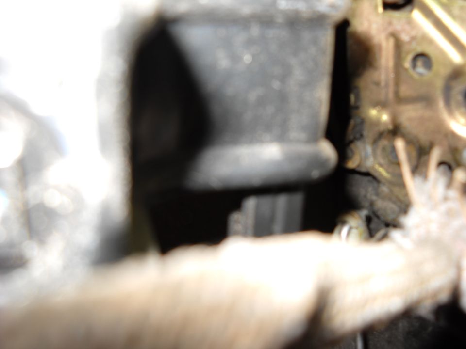 Close-up of a vehicle's internal door lock mechanism, showing metal components and a black rubber boot