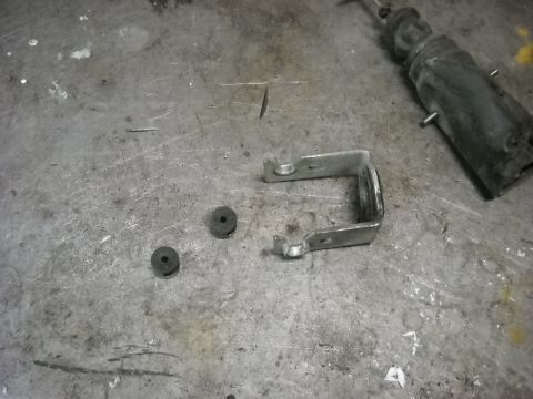 1993 Ford C-150 (Centurion Conversions) - Door lock actuator and bracket with two rubber grommets are shown on a workbench.