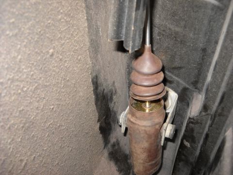 1993 Ford C-150 (Centurion Conversions) - This is a close-up view of a vehicle's door lock actuator rod, showing its rusty condition and rubber boot.